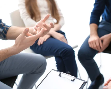 A diverse group of individuals seated in a circle, sharing experiences and providing mutual support during a group therapy session in a Dorset counseling center.